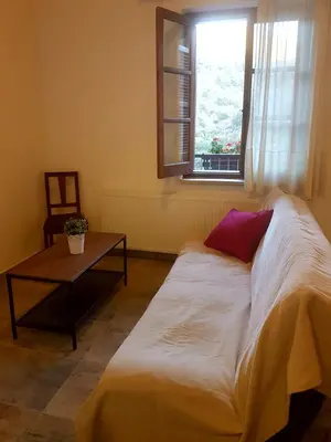 a bed in a room with a table and a window at Kalopanayiotis Museum Inn in Kalopanayiotis