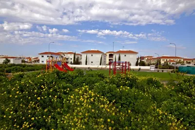 a playground with a red slide in a field of flowers at Mythical Sands Apartments in Protaras