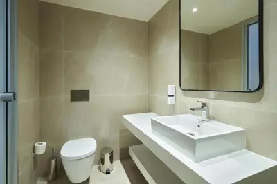 a bathroom with a sink and a toilet and a mirror at Maris Grand Waterpark Resort in Protaras