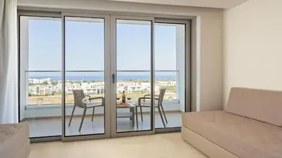 a room with sliding glass doors with a table and chairs at Maris Grand Waterpark Resort in Protaras