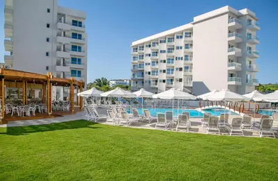 a pool with chairs and umbrellas next to a building at Vangelis Hotel & Suites in Protaras
