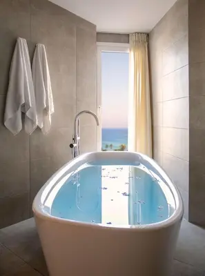 a bath tub in a bathroom with a view of the ocean at Vangelis Hotel & Suites in Protaras