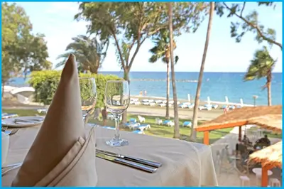 a table with two wine glasses on the beach at Poseidonia Beach Hotel in Limassol