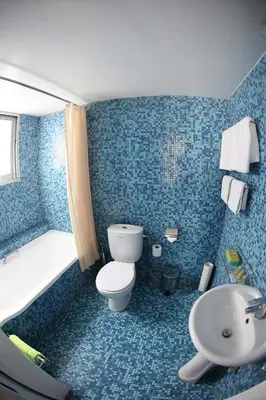 a blue tiled bathroom with a toilet and a sink at Asty Hotel in Nicosia