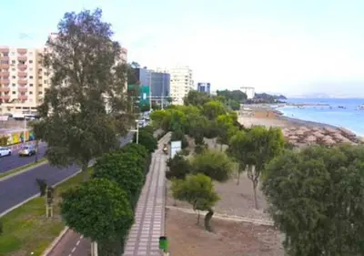 a city street with trees and a beach and buildings at Metro Court Apartments in Limassol