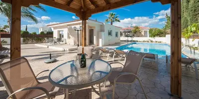 a patio with a table and chairs and a swimming pool at Villa Stefanie in Ayia Napa