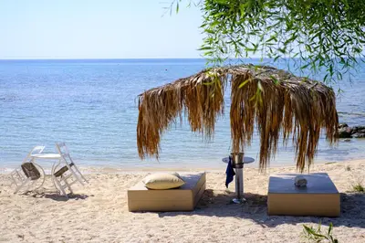 a beach with two chairs and a umbrella and a bed and a table at Thalassines Villas in Ayia Napa