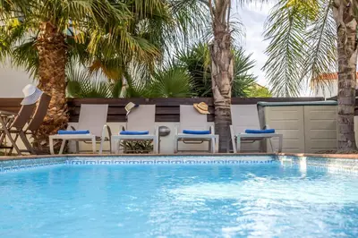 a swimming pool with chairs and palm trees at Villa Costas in Protaras