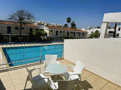 a patio with a table and chairs next to a swimming pool at Green Bungalows Hotel Apartments in Ayia Napa