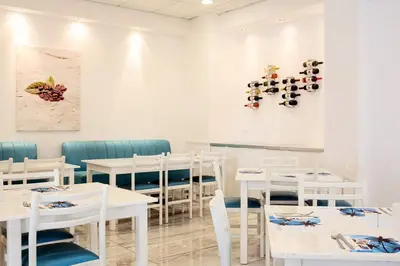 a white restaurant with white tables and chairs at Lantiana Gardens ApartHotel in Protaras