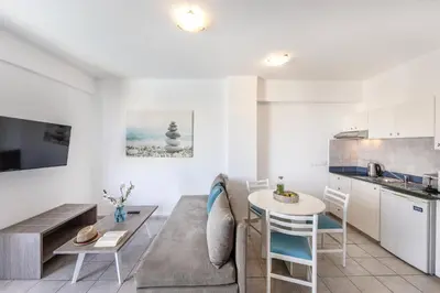 a kitchen and living room with a table and chairs at Lantiana Gardens ApartHotel in Protaras