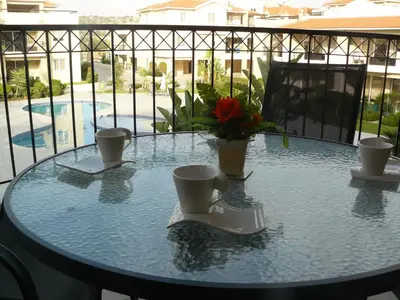 a glass table with two cups and a laptop on it at Pyla Gardens E108 in Pyla