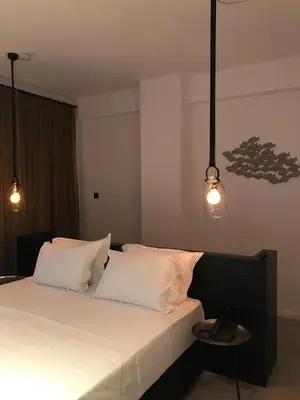 a bedroom with a bed with three pillows and two lights at Abacus Suites in Ayia Napa