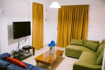 a living room with a green couch and a tv at Villa Costa Cornelia Homes in Ayia Napa