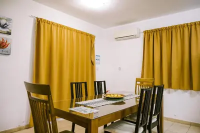 a dining room table with chairs and a yellow curtain at Villa Costa Cornelia Homes in Ayia Napa