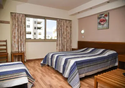 a bedroom with two beds and a window at Elysso Hotel in Larnaka