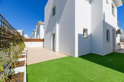 a courtyard with green grass in a white building at Sunrise Bay Villa #1 in Paralimni