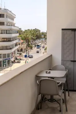 a table and chairs on a balcony with a view of a city at City Rendezvous One Bedroom Flat in Larnaka