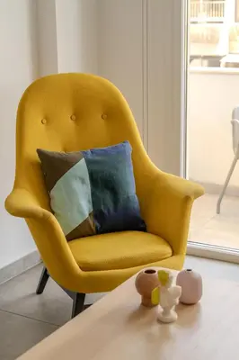 a yellow chair with pillows on a table at City Rendezvous One Bedroom Flat in Larnaka