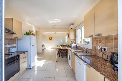 a large kitchen with white appliances and wooden cabinets at Villa Stephania in Ayia Napa