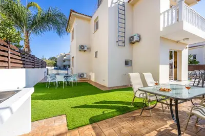 a backyard with green grass and a table and chairs at Villa Stephania in Ayia Napa