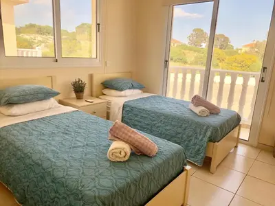 a bedroom with two beds and a balcony at Villa Stephania in Ayia Napa