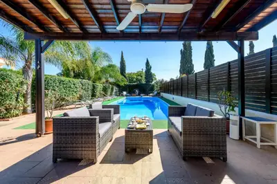 an outdoor patio with wicker furniture and a swimming pool at Villa Penelope in Protaras