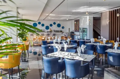a dining room with blue chairs and tables at Sun Hall Hotel in Larnaka