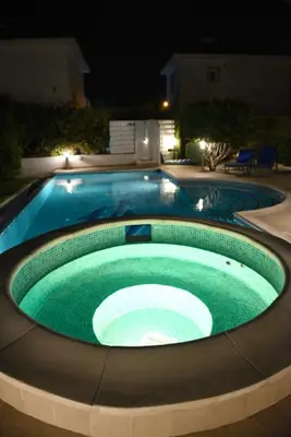 a swimming pool at night with a green pool at Karythia in Pyla