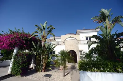 a building with palm trees and flowers in front of it at Karythia in Pyla