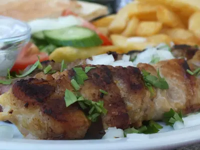 a plate of food with a piece of meat and french fries at Livas Hotel Apartments in Protaras