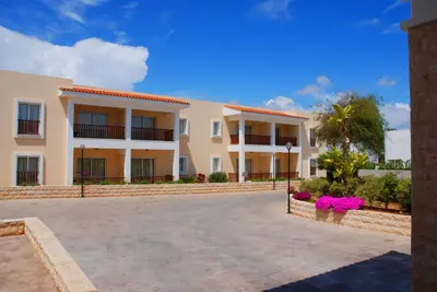 a large apartment building with a parking lot at Aktea Beach Village in Ayia Napa