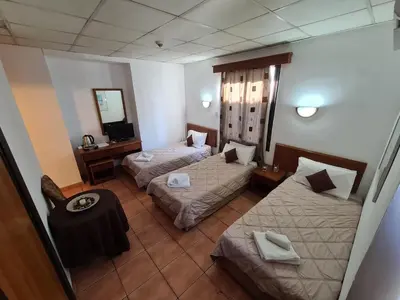 a hotel room with two beds and a mirror at Metropole Hotel in Limassol