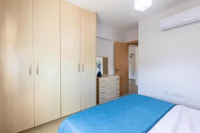 a bedroom with wooden cabinets and a blue bed at Tranquil Kyklades BC6, WALK to BEACH in Paralimni