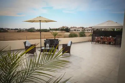 a patio with a table and chairs and an umbrella at Villa Elena in Ayia Napa