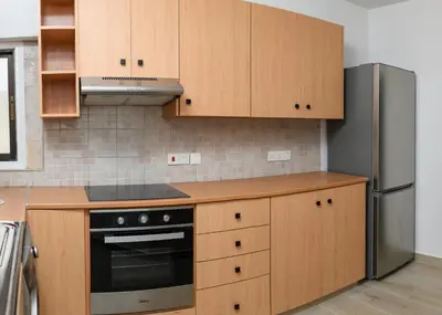 a kitchen with wooden cabinets and a stainless steel refrigerator at Ollies 3 Bedroom Apartment in Larnaka