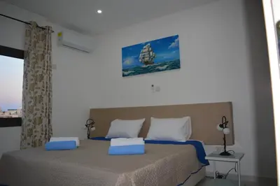 a bedroom with a bed with blue and white pillows at P.L Hermes Studios & Apartments in Larnaka