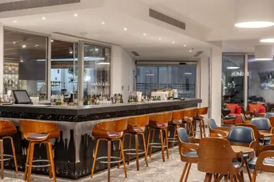 a bar in a restaurant with wooden stools at Park Beach Hotel in Limassol