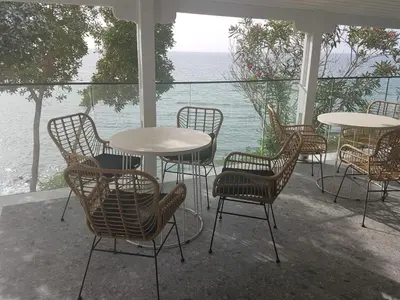 a patio with tables and chairs and a view of the water at E.J. Pyrgos Bay Hotel in Kato Pyrgos