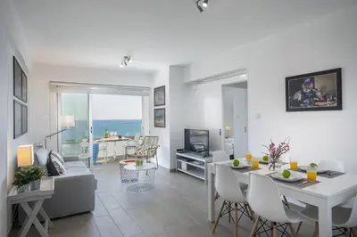 a living room with a dining table and a living room at Mackenzie Zoe Seafront Suite in Larnaka