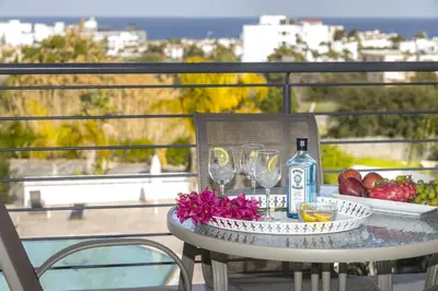 a table with wine glasses and fruit on a balcony at Protaras Palm Suite in Protaras