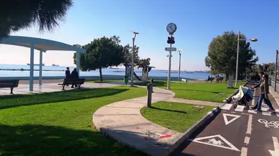 a park with people sitting on benches near the water at Poseidon Boutique Apartment 1 in Limassol