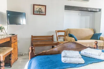 a living room with a bed and a tv at To Konatzi tou Flokka in Ayios Theodhoros