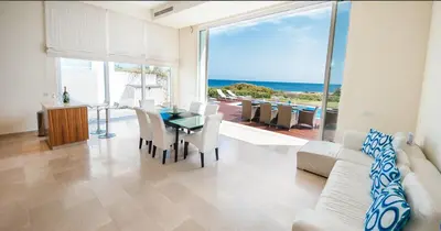 a living room with a table and a view of the ocean at Luxury Bay View Villa 20 Right On Τhe Beach in Protaras