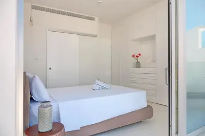 a white bedroom with a bed and a glass door at Seaview Luxury Villa Jacuzzi & Pool! 2 Min Beach in Protaras