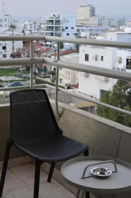 a chair and a table on a balcony with a view at Sunflower Hotel Apartments in Larnaka