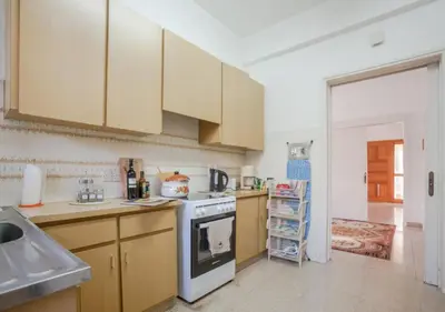 a kitchen with wooden cabinets and a white stove top oven at Sunny Family Home By The Beach in Limassol