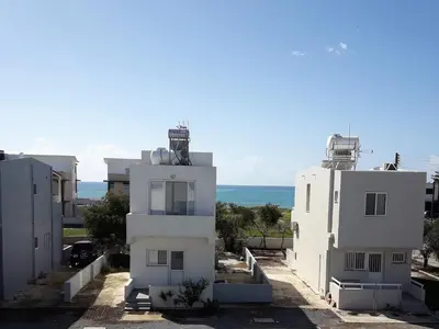 two white buildings with the ocean in the background at Sandy Beach Complex in Pervolia