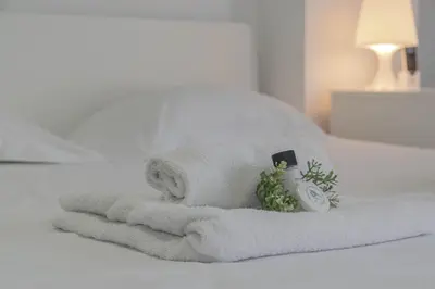 a pile of towels and a alarm clock on a bed at Sandy Beach Complex in Pervolia