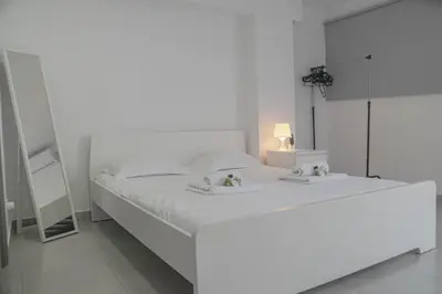 a white bedroom with a large white bed with two towels at Sandy Beach Complex in Pervolia